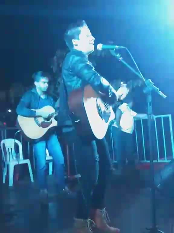 Diego Simonete cantando em palco sob iluminação azul