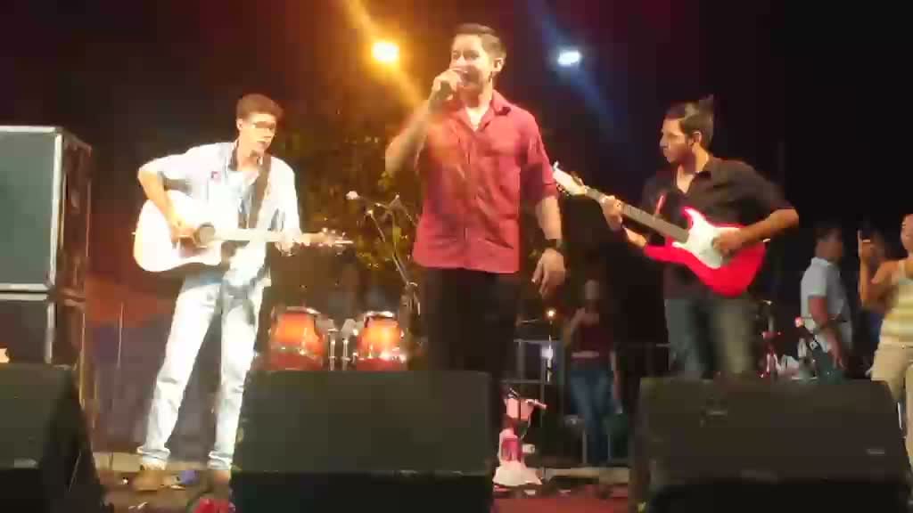 Diego Simonete cantando em palco com banda completa e iluminação de show